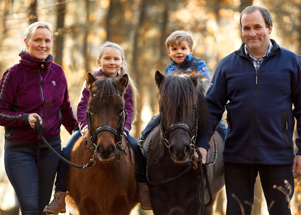 Maika und Malte Becker auf Ponys mit ihren Eltern im Wald
